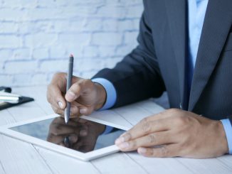 a man in a suit writing on a tablet