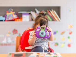 girl holding purple and green camera toy