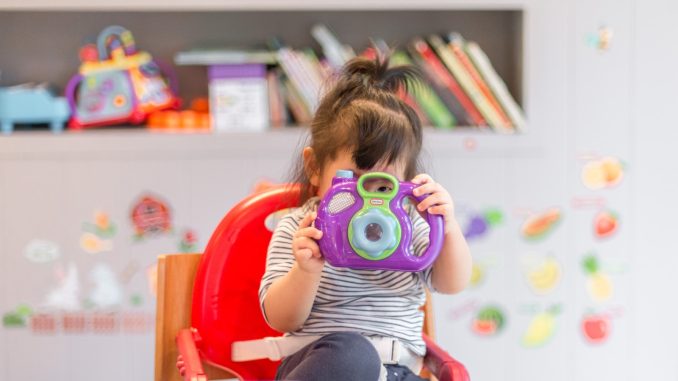 girl holding purple and green camera toy